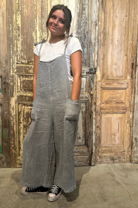 Person wearing gray overalls standing in front of a rustic wooden door.