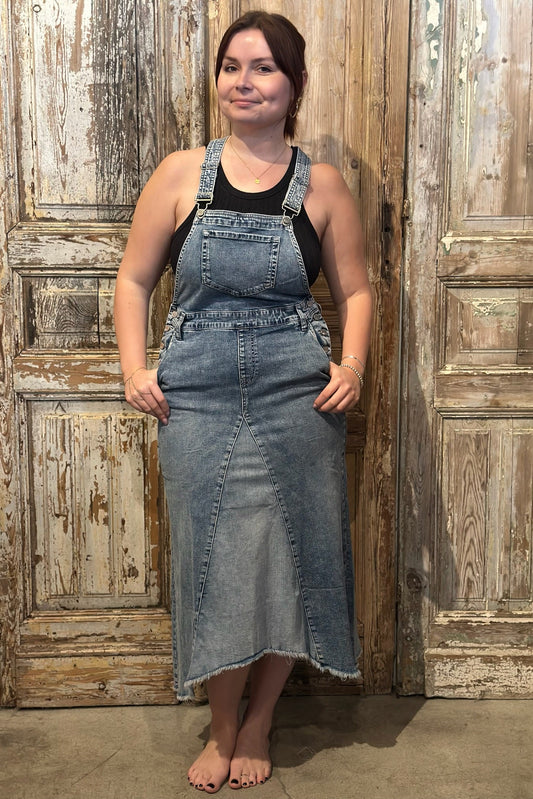 Woman wearing a denim dress standing in front of a wooden door.