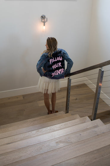 Trestles Clothing Company distressed denim jacket with Follow Your Dreams hand-painted in pink on the back