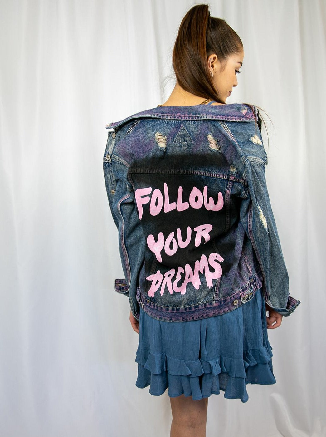 Trestles Clothing Company distressed denim jacket with hand-painted pink Follow Your Dreams text on the back