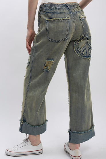 Trestles Clothing Company wide-leg distressed denim jeans with a peace sign patch on the back and elastic waistband.