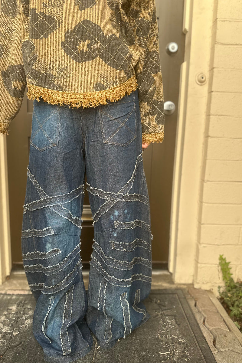 Trestles Clothing Company dark denim wide leg jeans with frayed fabric patches and distressed details on a person
