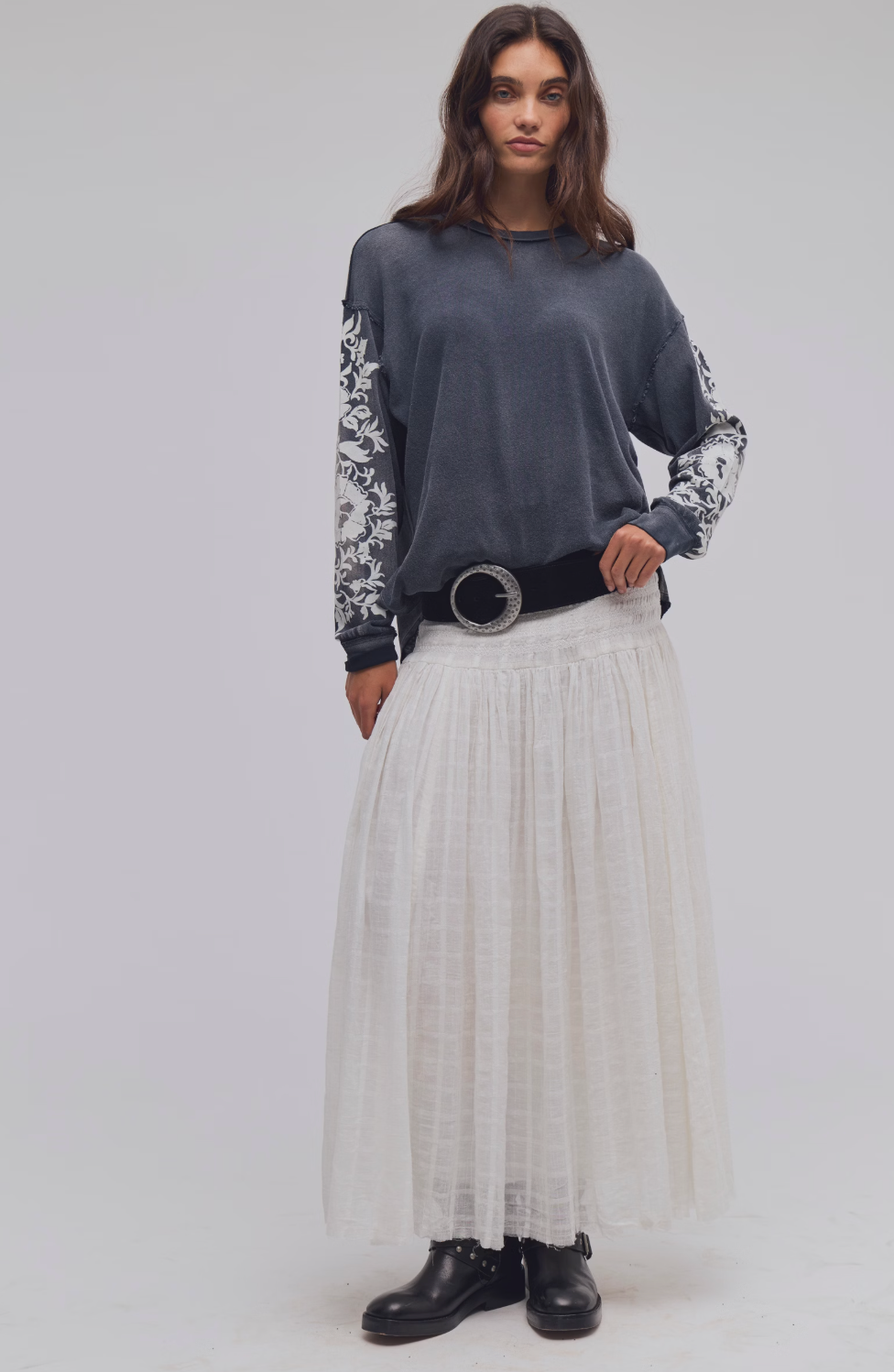Model wearing Trestles Clothing Company Flora long sleeve tee with grey floral sleeves and a white maxi skirt