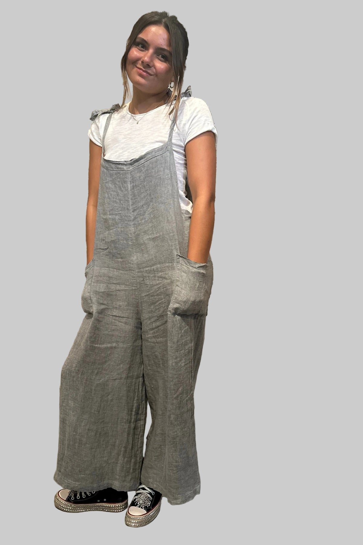 Person wearing gray overalls standing in front of a rustic wooden door.