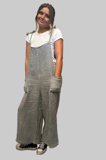Person wearing gray overalls standing in front of a rustic wooden door.