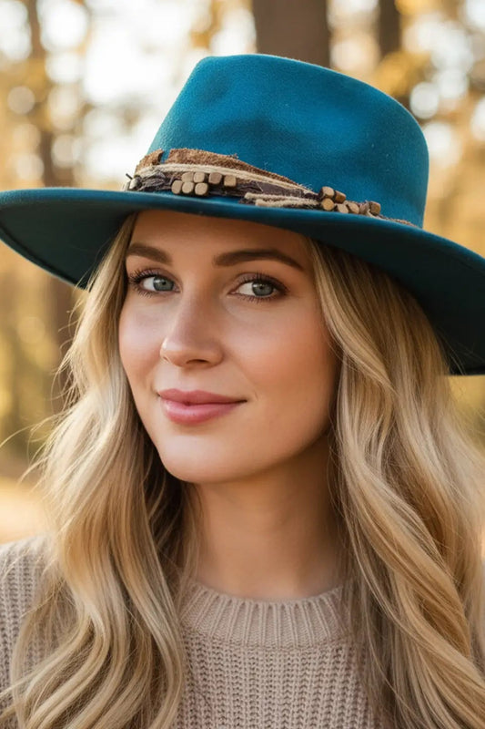 Woman wearing a teal hat with a brown band in a forest setting