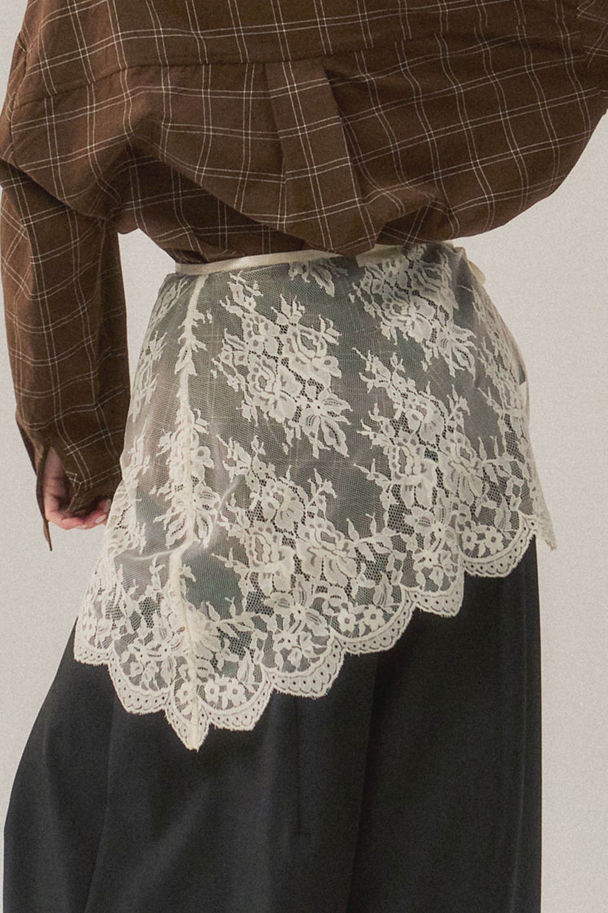 Trestles Clothing Company asymmetrical white lace skirt overlay worn over dark trousers for a boho layered look.