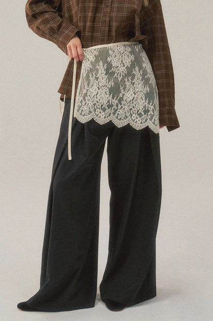 Trestles Clothing Company white asymmetrical lace skirt overlay worn over black trousers and a brown plaid shirt.