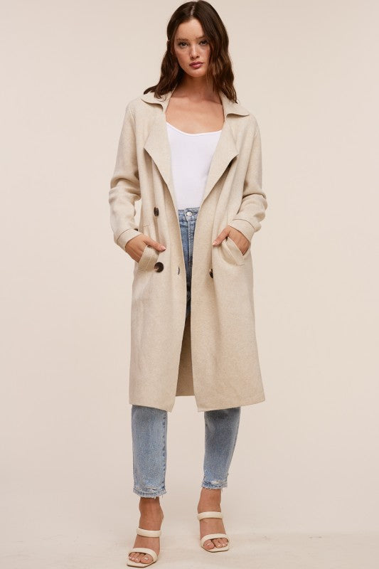 Model wearing a beige Trestles Clothing Company Beckham midi sweater coat over a white top and blue jeans
