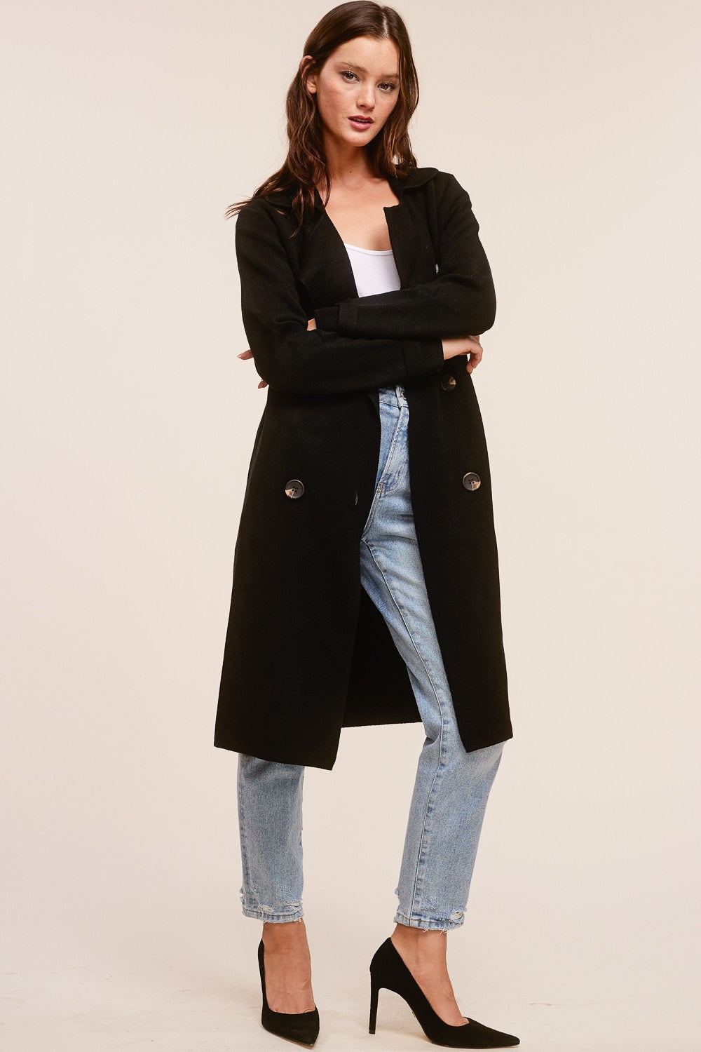 Model wearing a black Trestles Clothing Company Beckham midi sweater coat over a white top and light wash jeans.