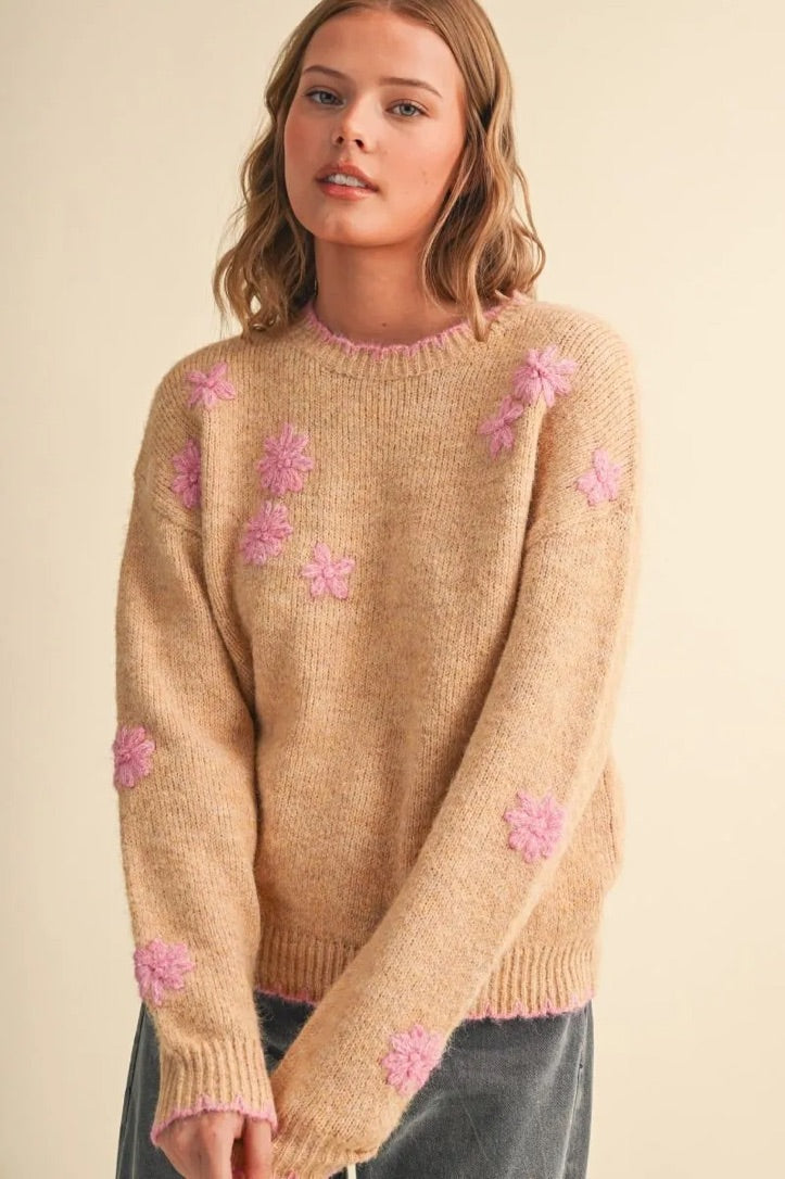 Trestles Clothing Company beige knit sweater featuring pink floral embroidery and scalloped contrast trim on a model.