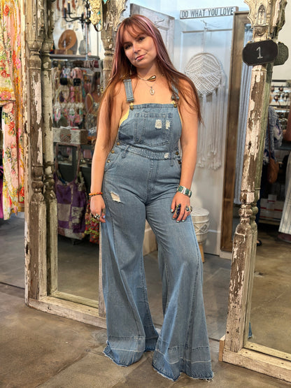 Trestles Clothing Company extreme bell bottom denim overalls with distressed details worn by a model in a boutique