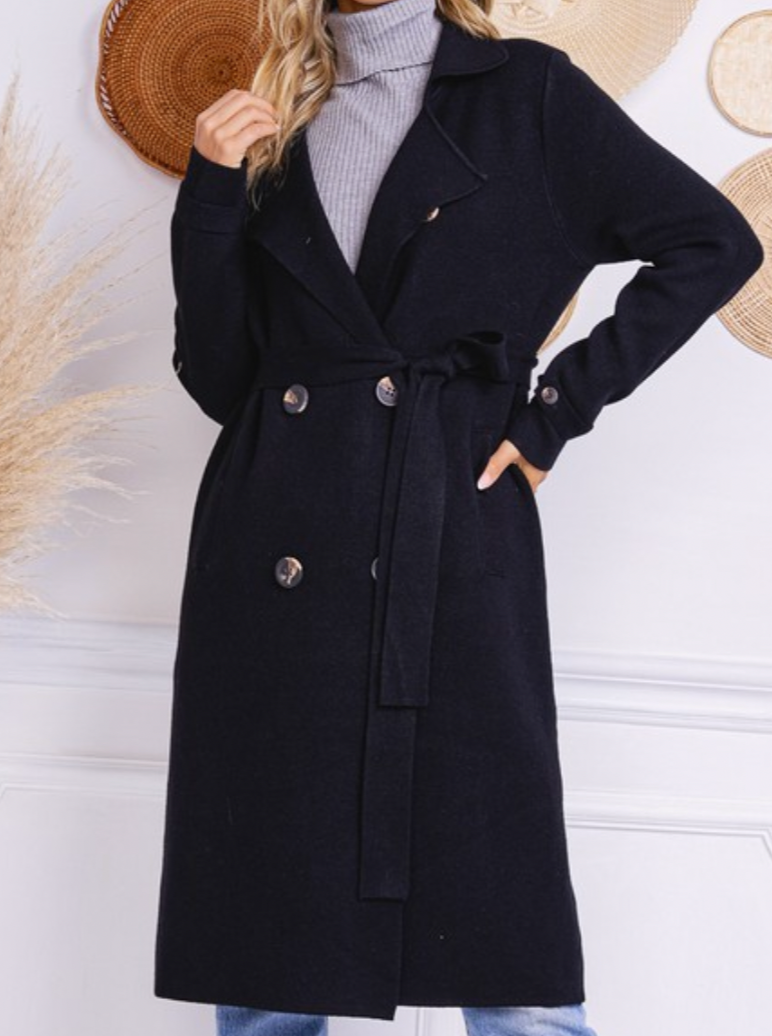 Model wearing a black Trestles Clothing Company Beckham midi sweater coat with a belted waist and button details.