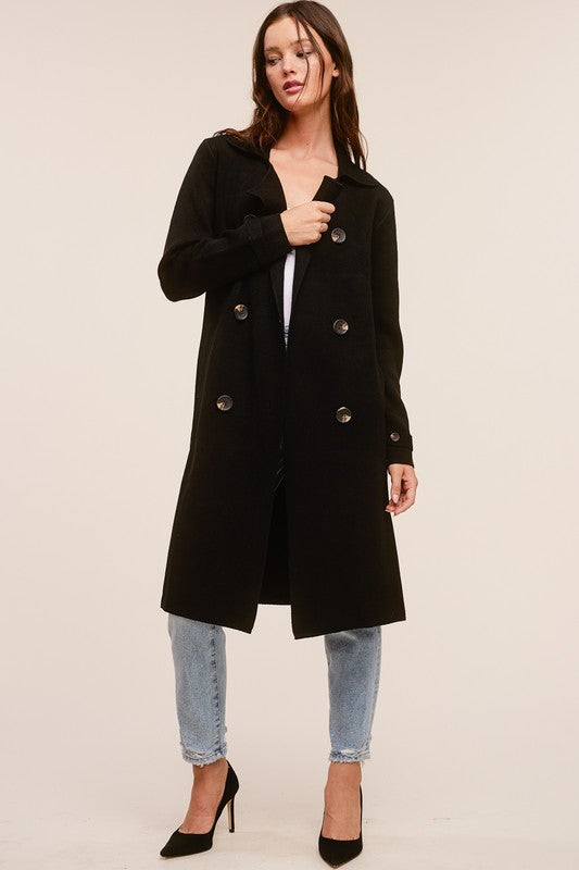Model wearing a black Trestles Clothing Company Beckham midi sweater coat over jeans and black heels