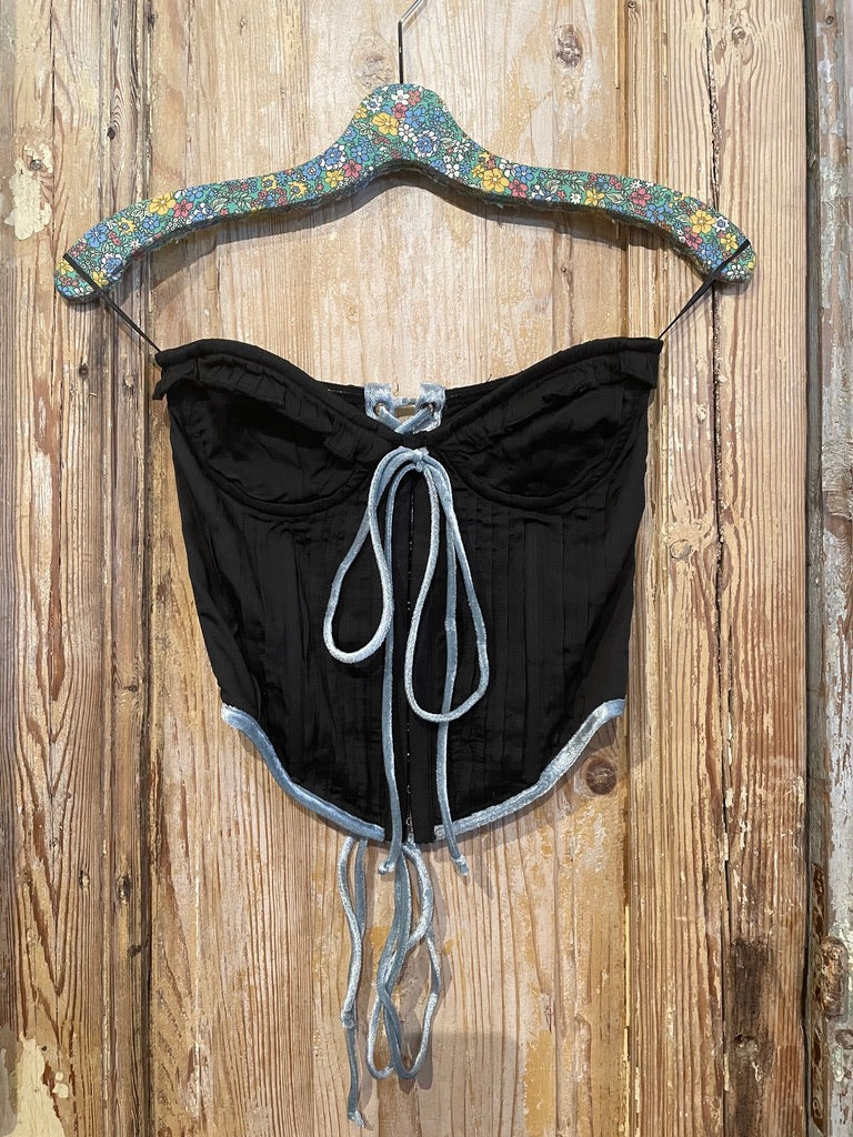 Trestles Clothing Company black corset top with blue velvet trim, ruffle front, and adjustable tie-up details.