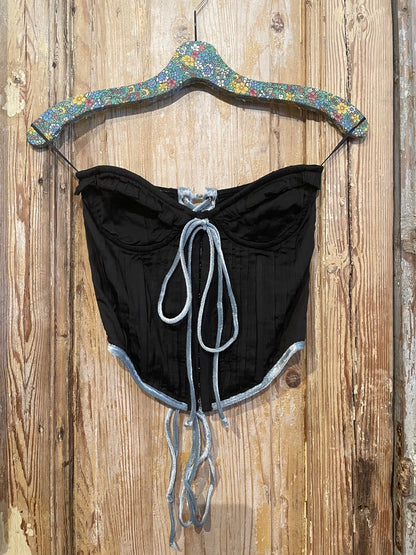 Trestles Clothing Company black corset top with blue velvet trim, ruffle front, and adjustable tie-up details.