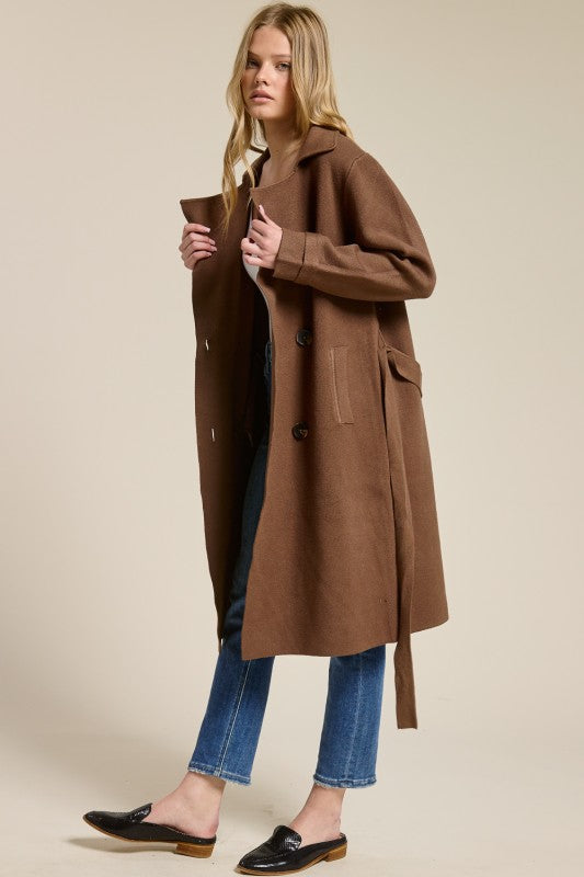 Model wearing a brown Trestles Clothing Company Beckham midi sweater coat with an optional belt over jeans