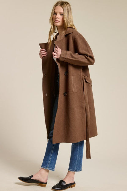 Model wearing a brown Trestles Clothing Company Beckham midi sweater coat with an optional belt over jeans
