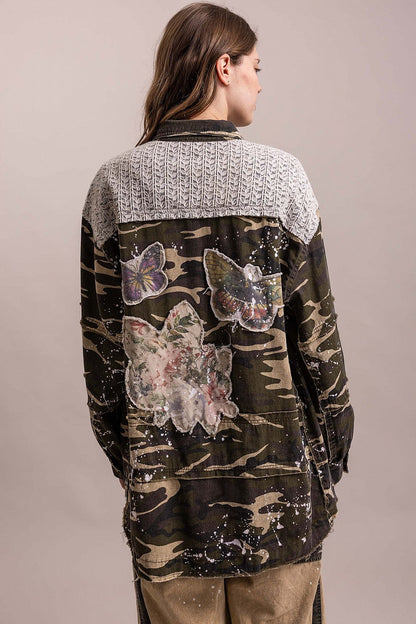Trestles Clothing Company camo shacket with floral and butterfly patches, paint splatters, and a knit back panel.