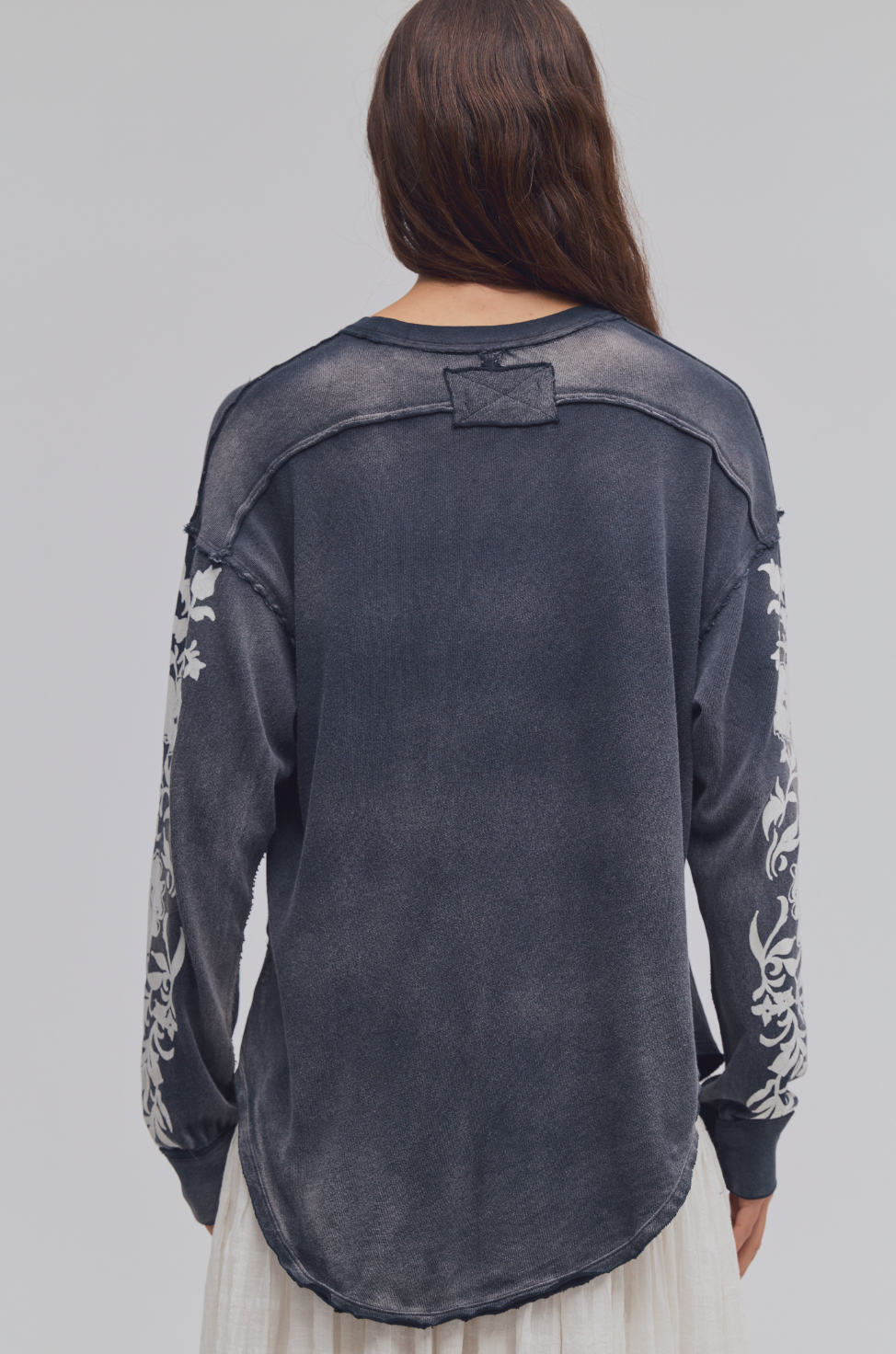 Back view of Trestles Clothing Company Flora long sleeve tee in washed black cotton with white floral sleeve detail