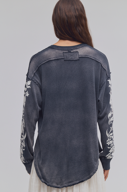 Back view of Trestles Clothing Company Flora long sleeve tee in washed black cotton with white floral sleeve detail