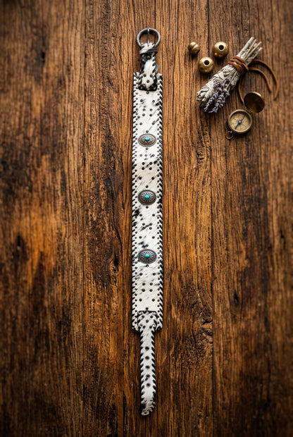 Trestles Clothing Company wide cowhide leather belt with turquoise conchos and studs on a rustic wooden background.