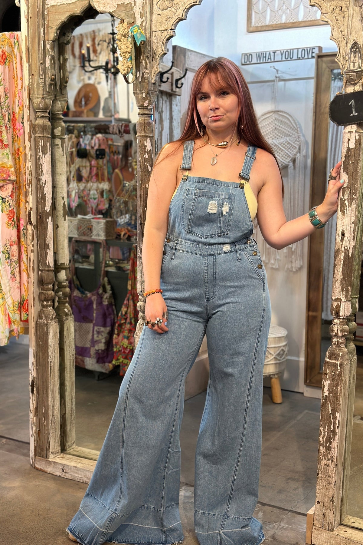 Trestles Clothing Company light wash denim overalls with extreme bell bottoms worn by a model in a boutique setting