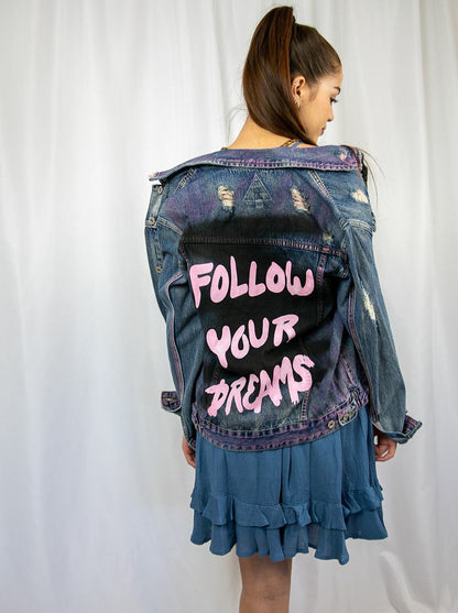 Trestles Clothing Company distressed denim jacket with hand-painted pink Follow Your Dreams text on the back