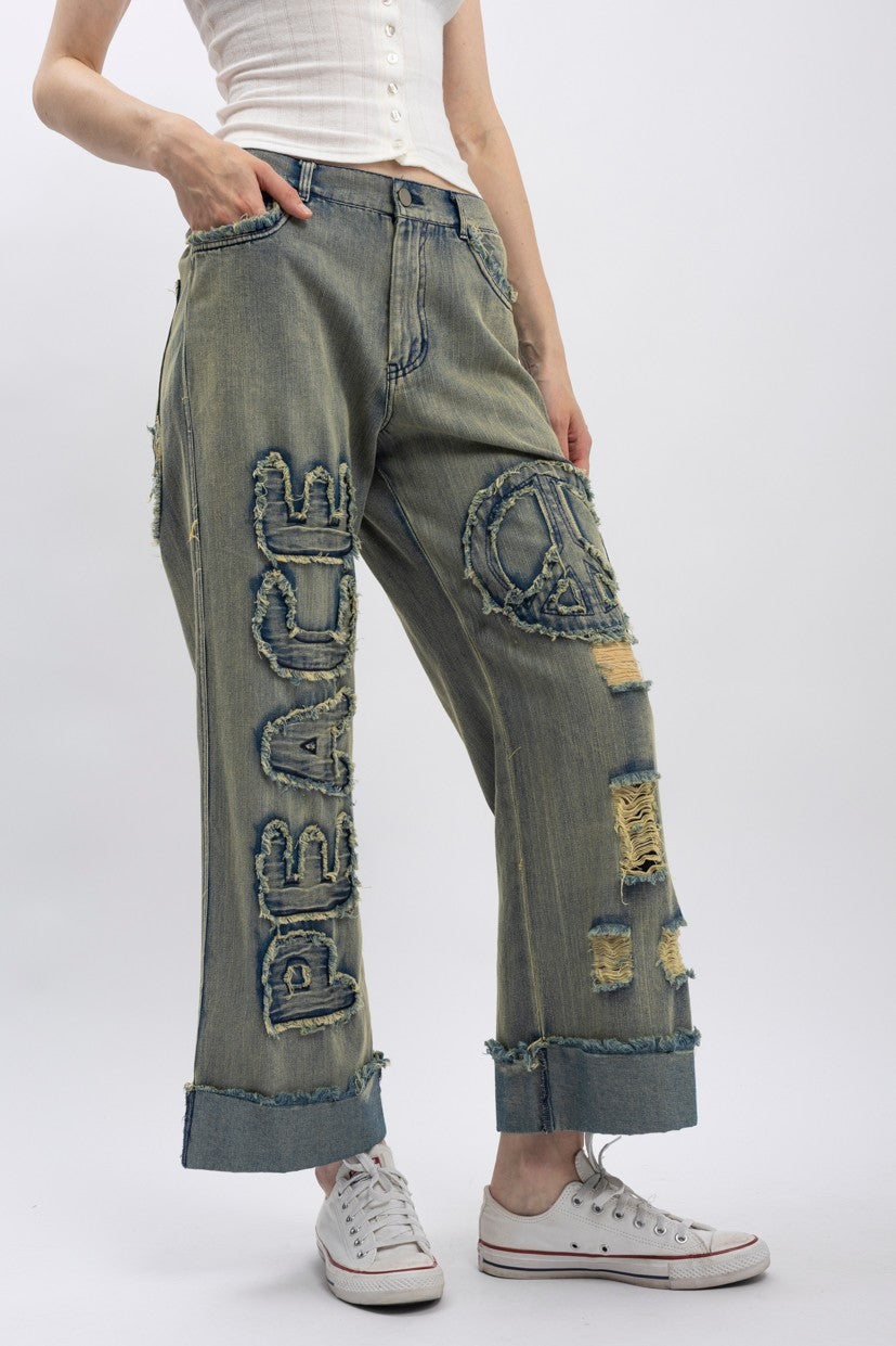 Trestles Clothing Company wide-leg distressed denim jeans with peace applique and vintage wash finish.