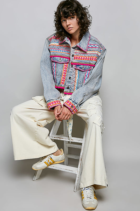Trestles Clothing Company cropped denim jacket with vibrant hand-embroidered Aztec motifs, pink accents, and beadwork.