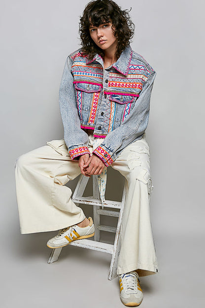 Trestles Clothing Company cropped denim jacket with vibrant hand-embroidered Aztec motifs, pink accents, and beadwork.