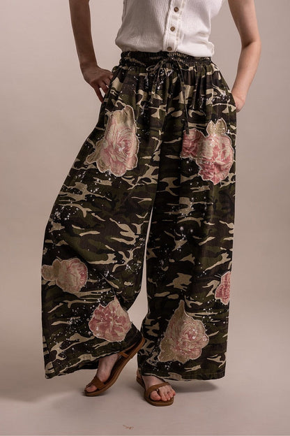Trestles Clothing Company wide leg camo pants featuring pink floral patches, paint splatter details, and tie waist.