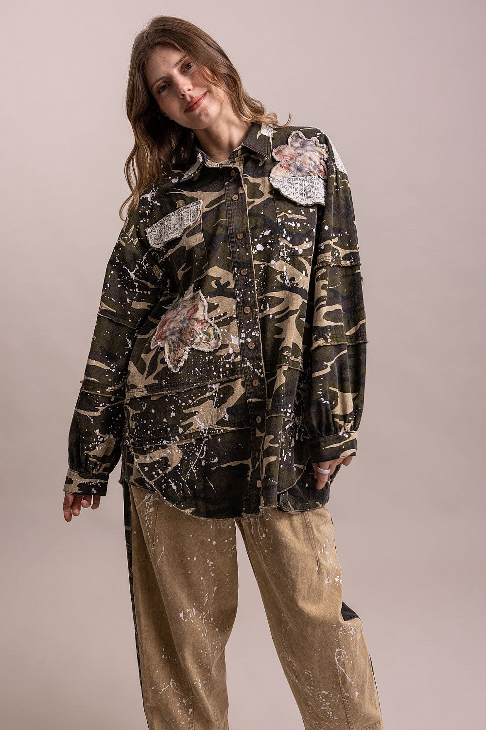 Trestles Clothing Company camo shacket with floral patches, paint splatters, and button front on a female model.