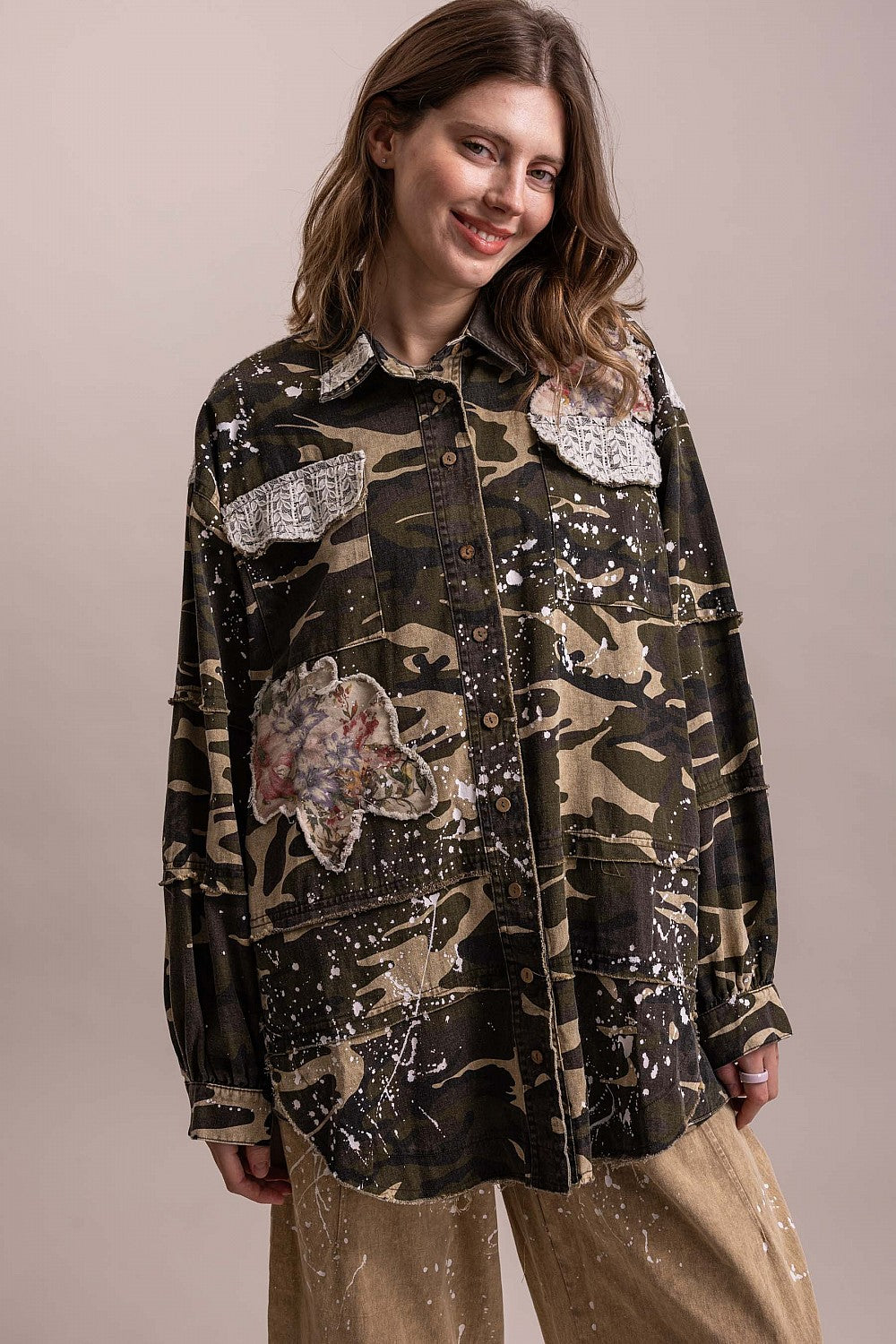 Trestles Clothing Company camo shacket with floral patches, paint splatters, and button front on a smiling model