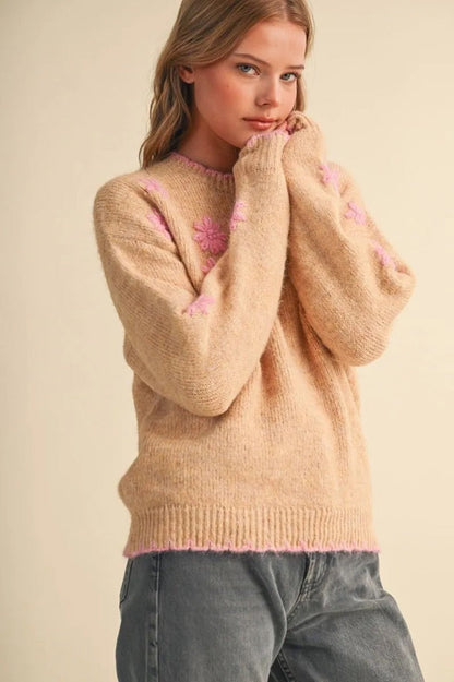 Trestles Clothing Company beige knit sweater with pink floral embroidery and scalloped trim worn by a blonde model