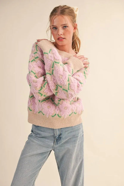 Model wearing a Trestles Clothing Company fuzzy floral knit sweater with pink flowers and beige ribbed trim.