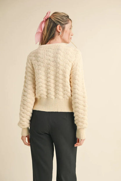 Trestles Clothing Company ivory knit cardigan with textured pattern, long puff sleeves, and ribbed hem, back view