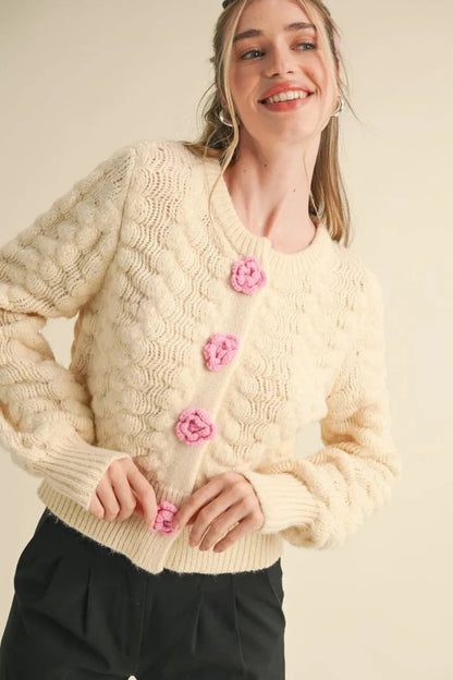 Trestles Clothing Company ivory knit cardigan with pink rosette buttons and textured floral pattern on a model