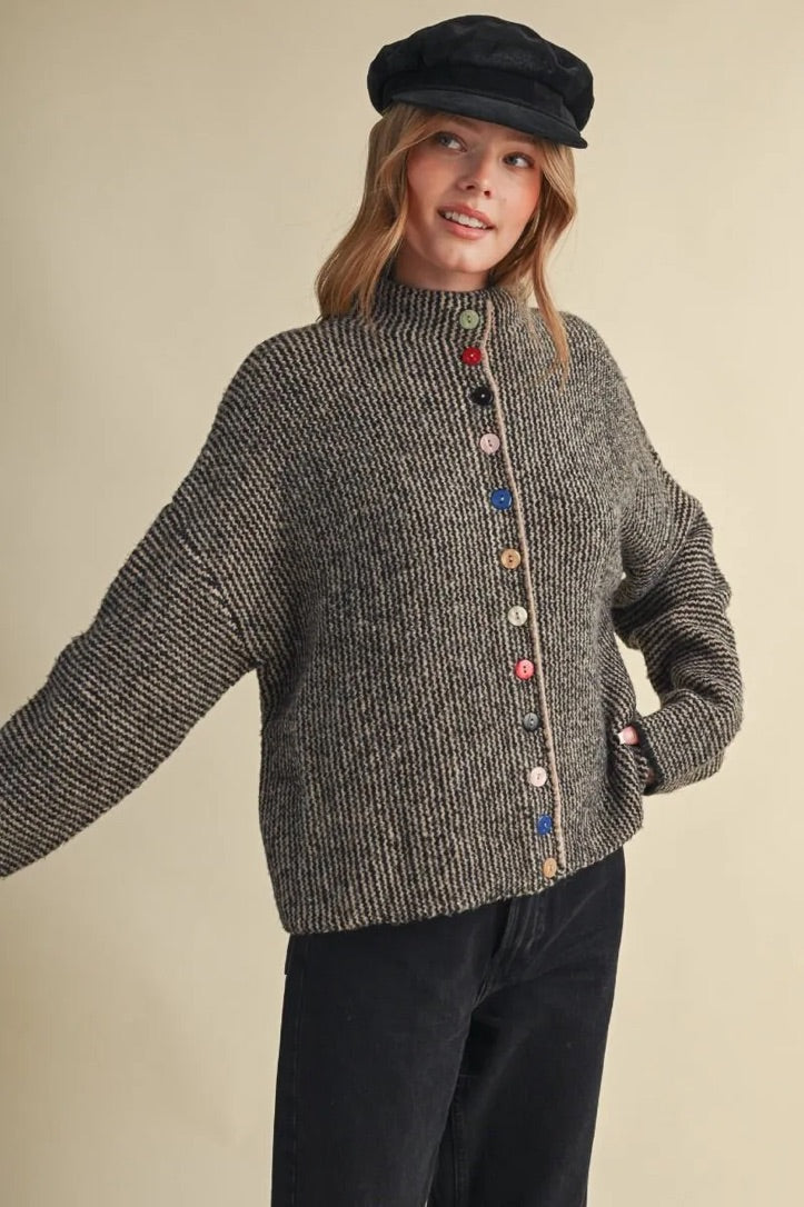 Model wearing a Trestles Clothing Company cozy grey knit sweater featuring unique mismatched colorful buttons