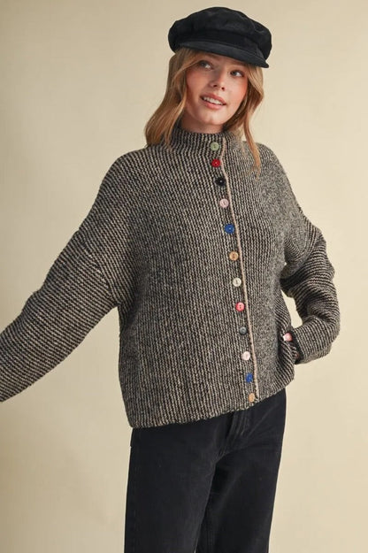 Model wearing a Trestles Clothing Company cozy grey knit sweater featuring unique mismatched colorful buttons