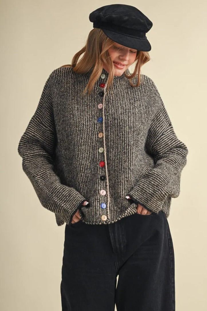 Model wearing a Trestles Clothing Company cozy grey textured sweater with unique mismatched colorful buttons.