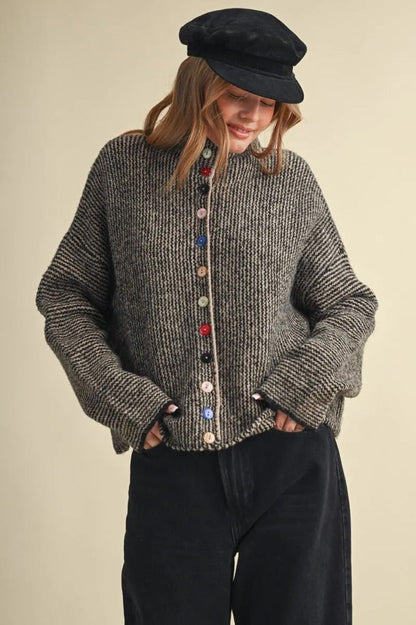 Model wearing a Trestles Clothing Company cozy grey textured sweater with unique mismatched colorful buttons.