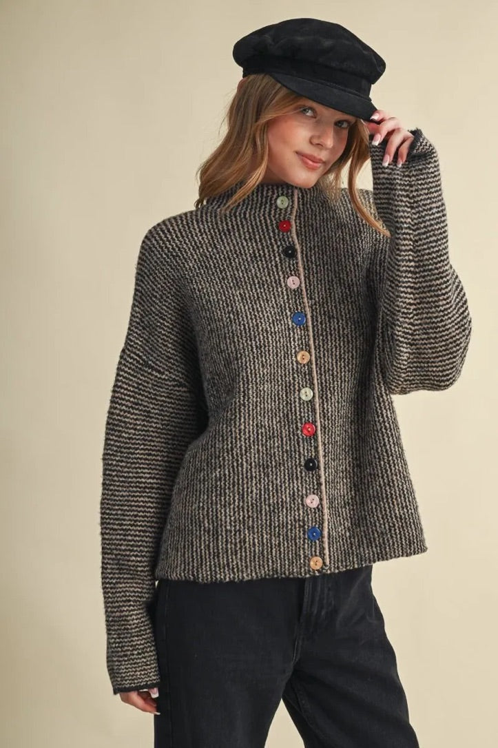 Trestles Clothing Company cozy knit sweater with mismatched colorful buttons worn by a woman in a black cap