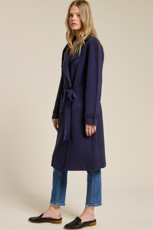 Model wearing a navy blue Trestles Clothing Company Beckham midi sweater coat with a belted waist over jeans