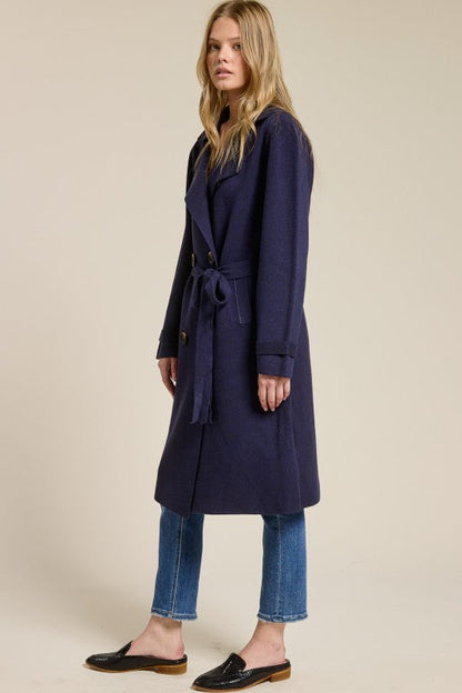 Model wearing a navy blue Trestles Clothing Company Beckham midi sweater coat with a belted waist over jeans