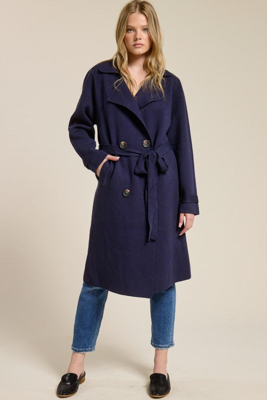 Model wearing a navy blue Trestles Clothing Company Beckham midi sweater coat with a tie belt over jeans