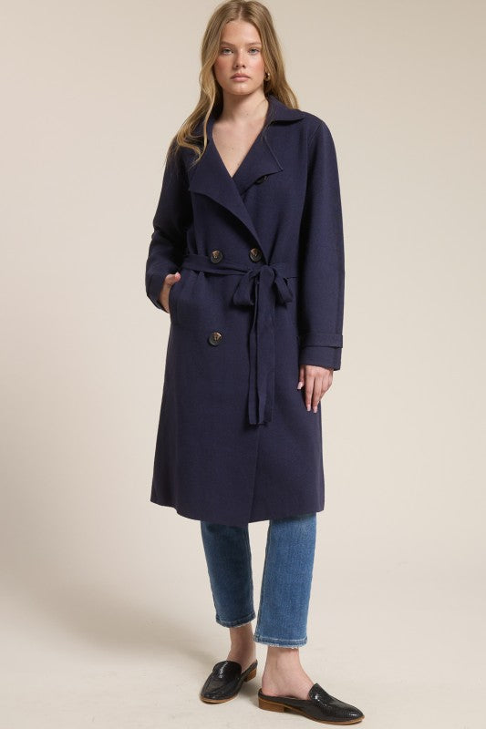 Model wearing a navy blue Trestles Clothing Company Beckham midi sweater coat with an optional tie belt over jeans.