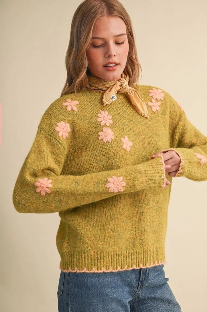 Trestles Clothing Company olive green knit sweater with pink floral embroidery and scalloped trim worn by a model