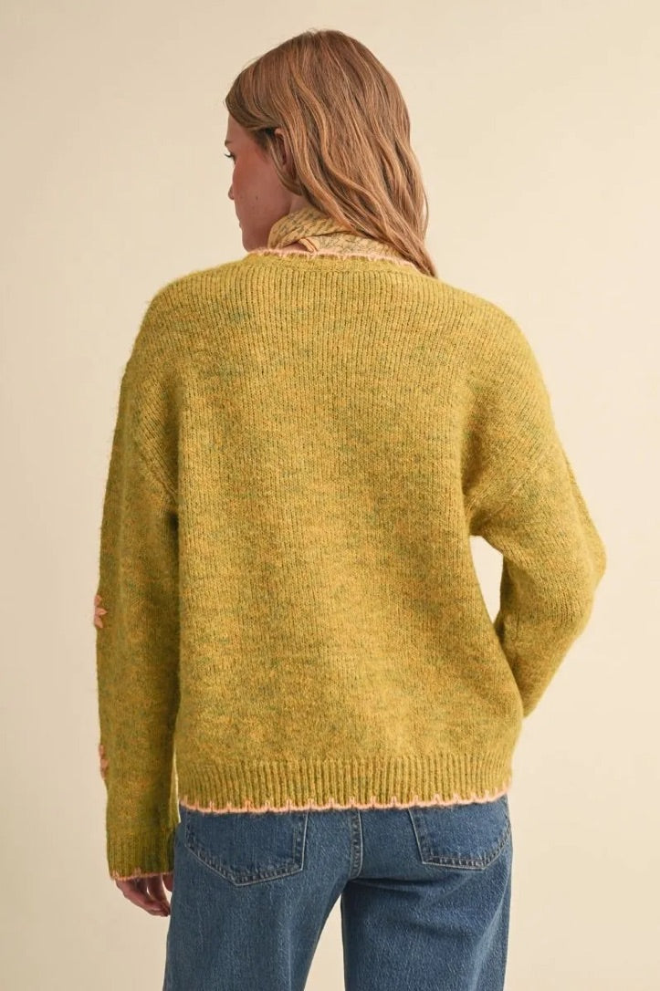 Back view of a Trestles Clothing Company knit sweater in mustard yellow with pink scalloped trim and drop shoulders.