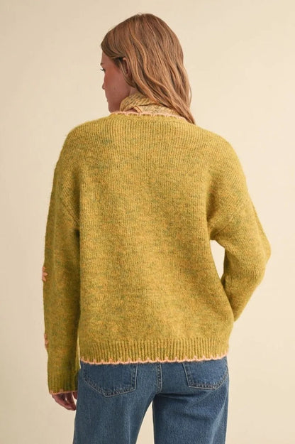 Back view of a Trestles Clothing Company knit sweater in mustard yellow with pink scalloped trim and drop shoulders.